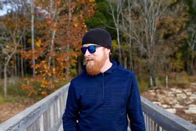 Bearded man standing on footbridge against sky