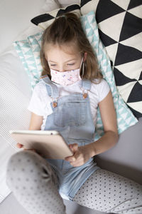 Girl using mobile phone on sofa at home