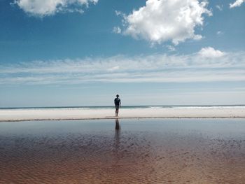 Mid distance view of man standing at beach against sky