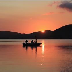 Silhouette boat in lake against orange sky