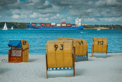 Hooded chairs on beach against sky