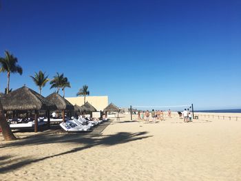 People on beach against clear blue sky