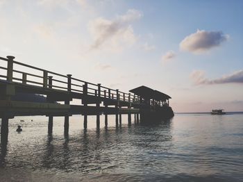 Silhouette pier over sea against sky during sunset