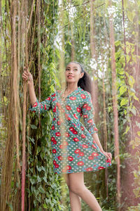 Young woman standing against trees