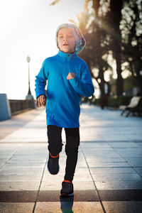 Portrait of boy standing on footpath