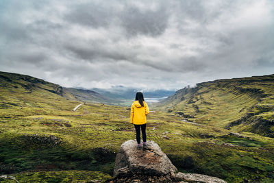 Rear view of man standing on yellow road against sky