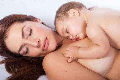 High angle view of shirtless mother and daughter sleeping over white background