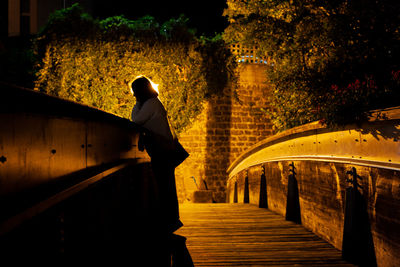 Woman standing on footbridge at night