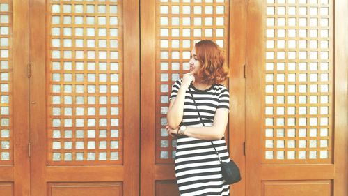 Rear view of young woman standing against window