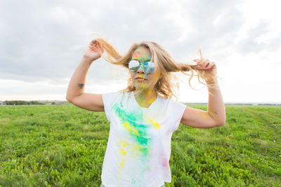 Full length of young woman standing on field against sky