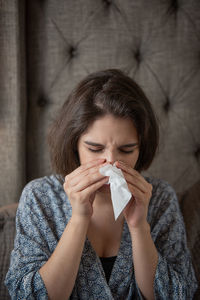 Woman with tissue paper sneezing at home