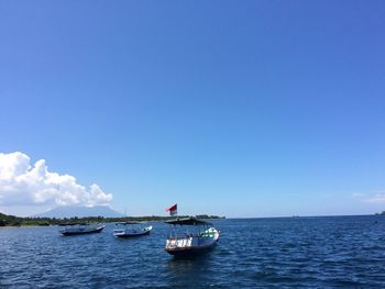 Boats sailing in sea against blue sky