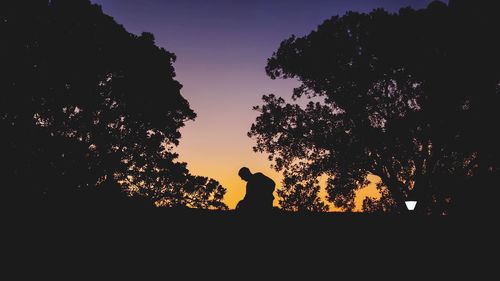 Silhouette of man standing by tree against clear sky