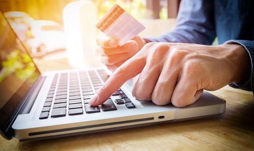 Close-up of man using laptop on table