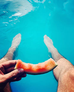 Midsection of person holding ice cream in swimming pool