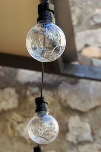 Close-up of light bulb hanging against wall