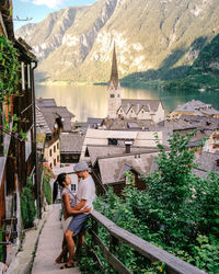 People sitting on mountain by lake against mountains