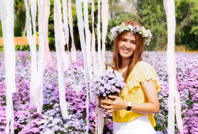 Portrait of smiling woman standing against purple flowering plants