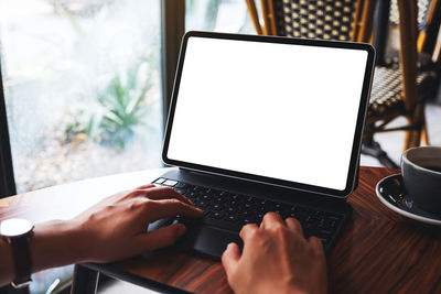 Cropped hands using laptop at table