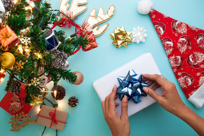 Cropped image of woman holding christmas decoration with various objects on table