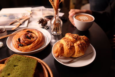 Close-up of coffee served and croissants on table