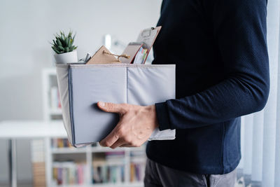 Midsection of man holding box in office