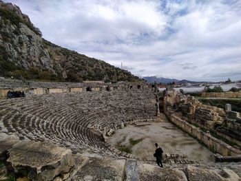 High angle view of old ruins on mountain against cloudy sky