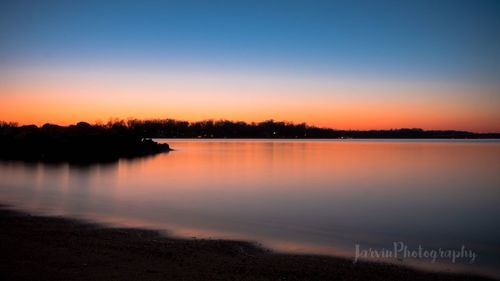 Reflection of trees in water at sunset