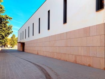 Empty footpath by building against sky