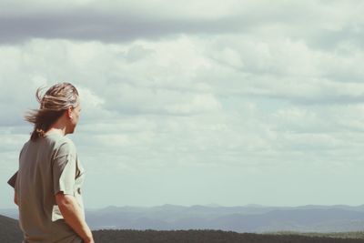 Man looking at view standing against cloudy sky