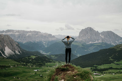 Woman standing on top of the rock overlooking the mountains