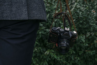Midsection of man with camera against plants