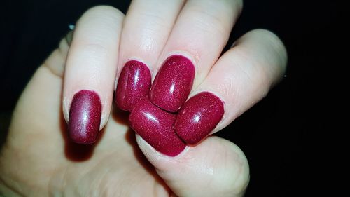 Close-up of hand holding strawberry over black background