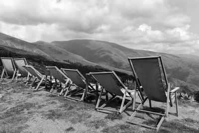 Chairs and tables on mountain against sky
