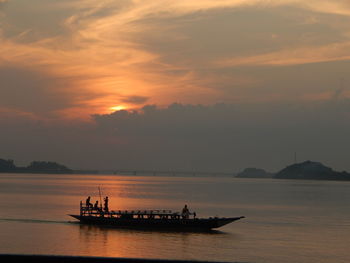 Silhouette boat sailing in sea against sky during sunset