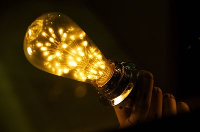 Close-up of illuminated light bulb against black background