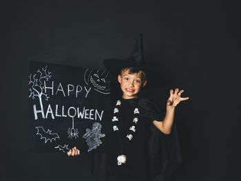 Portrait of boy standing against black background