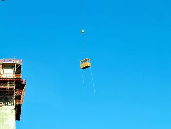 Low angle view of crane against clear sky