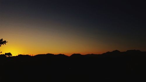 Silhouette landscape against clear sky during sunset