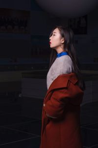 Side view of thoughtful young woman looking away while standing in darkroom