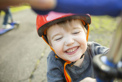 Smiling young boy wearing red helmet while playing outside at home