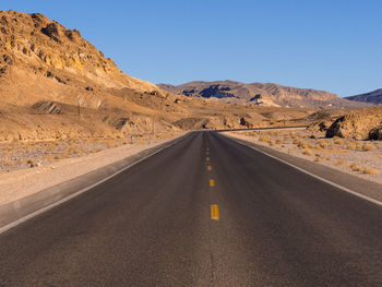 Empty road amidst desert against sky