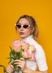 Portrait of woman with pink rose against yellow background