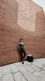 Full length of man standing on footpath against wall