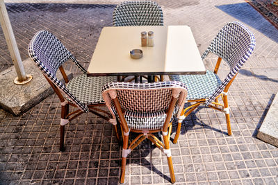 High angle view of empty chairs and tables at sidewalk cafe