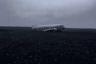 Abandoned airplane on landscape against sky