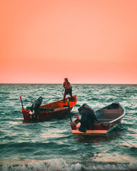 People in boat on sea against sky during sunset