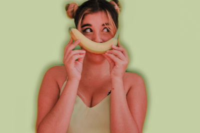Portrait of young woman holding food against white background
