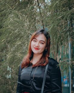 Portrait of smiling woman standing against plants