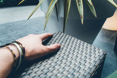 Cropped hand of woman on wicker sofa